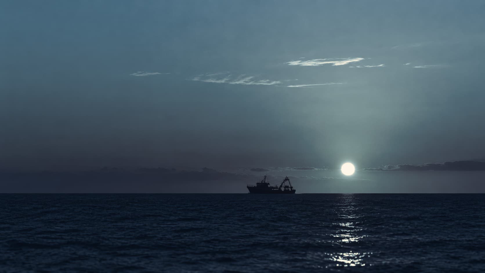 Fishing vessel silhouetted against the Atlantic horizon at sunset
